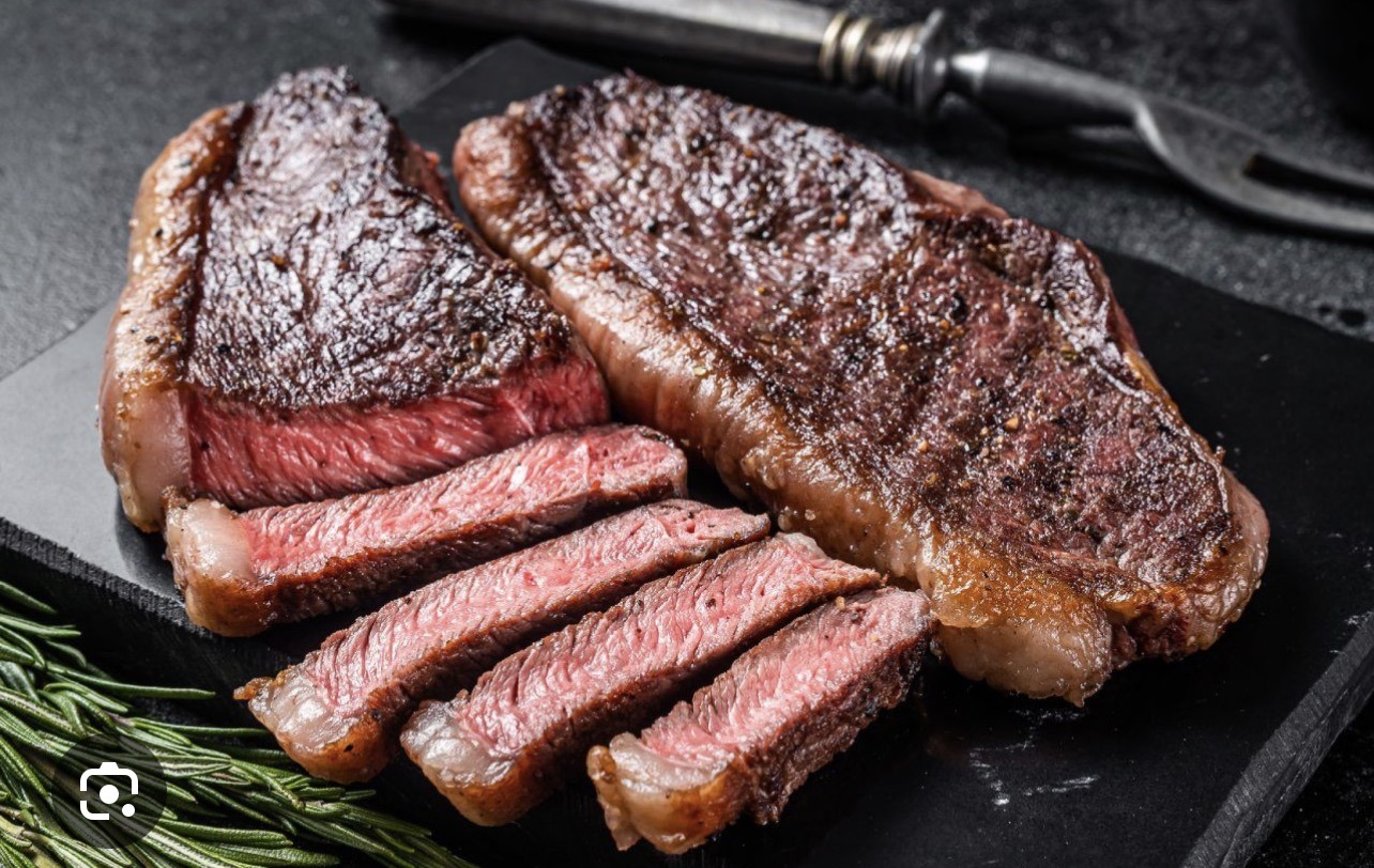 Picanha grelhada fatiada, servida ao ponto em uma tábua preta